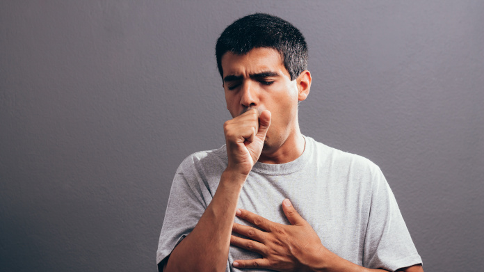 Man, coughing and holding his chest
